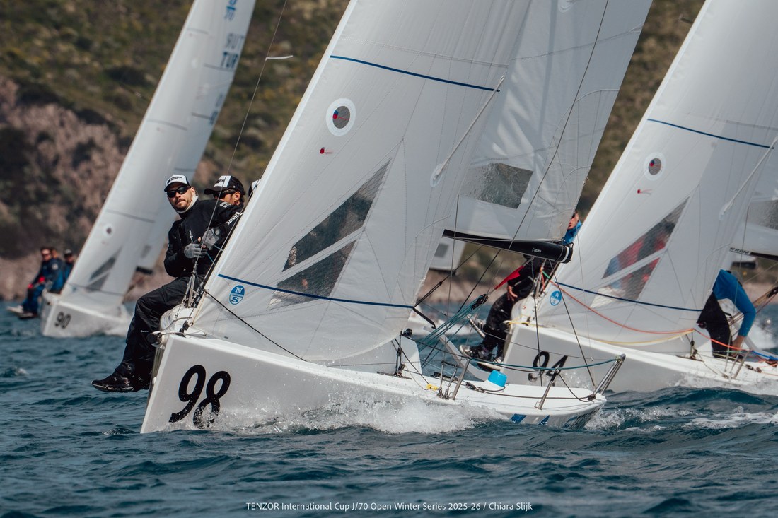 J/70 hull 98 racing hard along a rocky coastline
